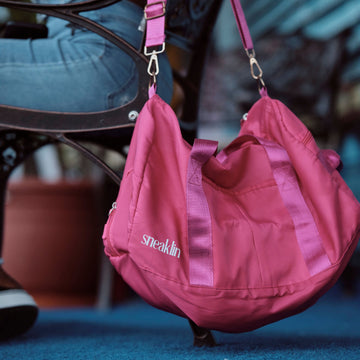 Pink bag with 'sneakkin' logo on a blue surface